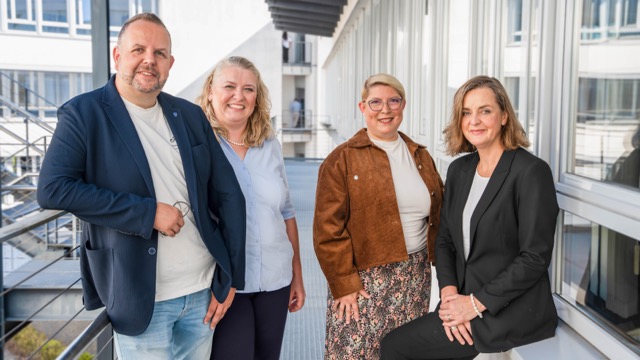 Ein Mann und drei Frauen vor einem Gebäude