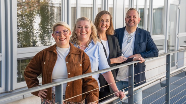 Drei Frauen und ein Mann stehend am Geländer